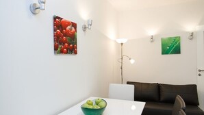 Ein modernes Wohnzimmer mit einem weißen Tisch, einem schwarzen Sofa und einer grünen Schüssel mit Äpfeln.