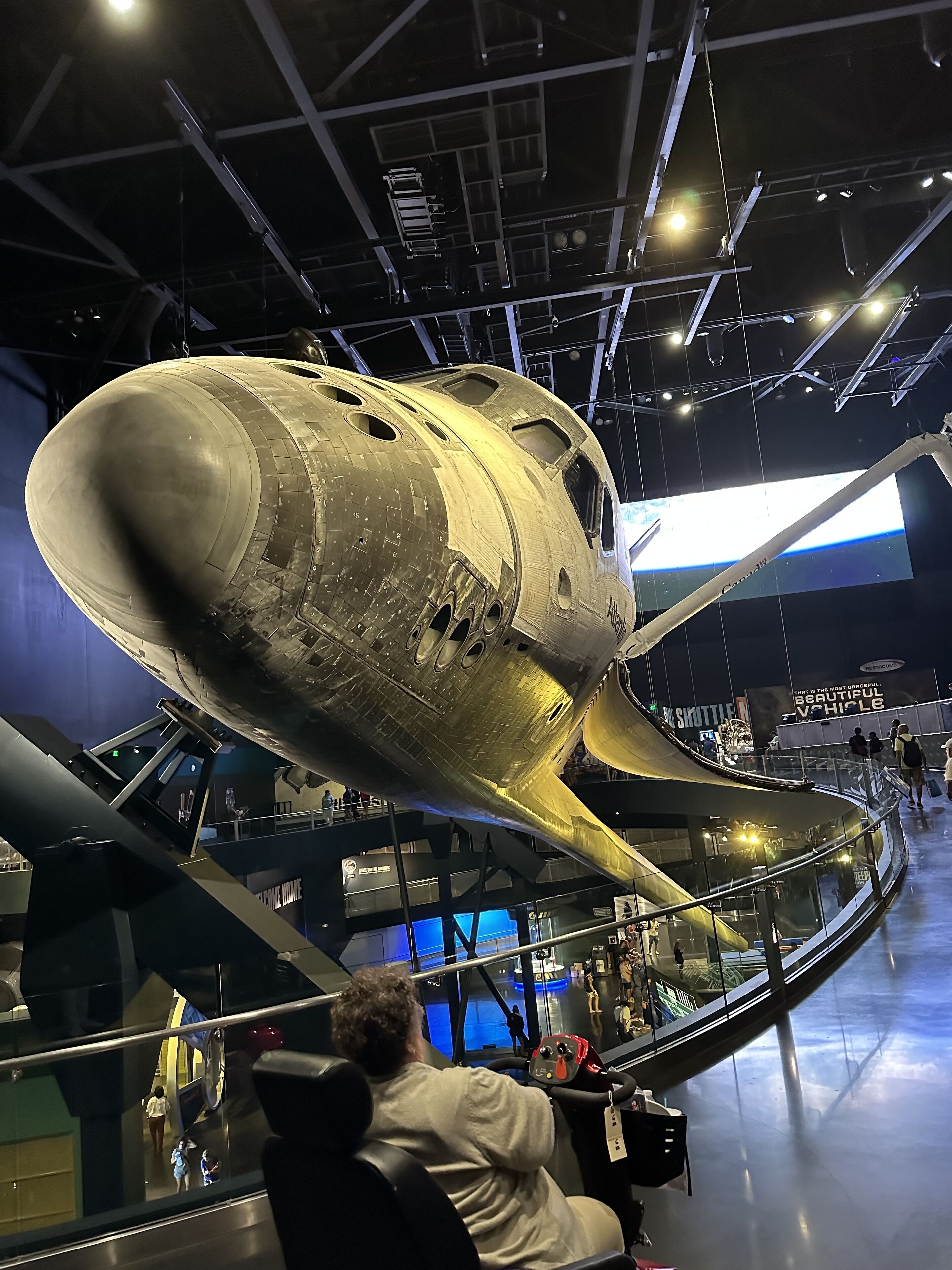 Un transbordador espacial exhibido en un museo, con una persona sentada en un simulador de cabina.