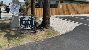 A parking area with a 'TOW AWAY' sign, a 'SHIPS 1145 WHEEL' sign, and a wooden fence. - Direct Oceanfront  South Cocoa Beach. Watch launches from Balcony. (Cocoa Beach)