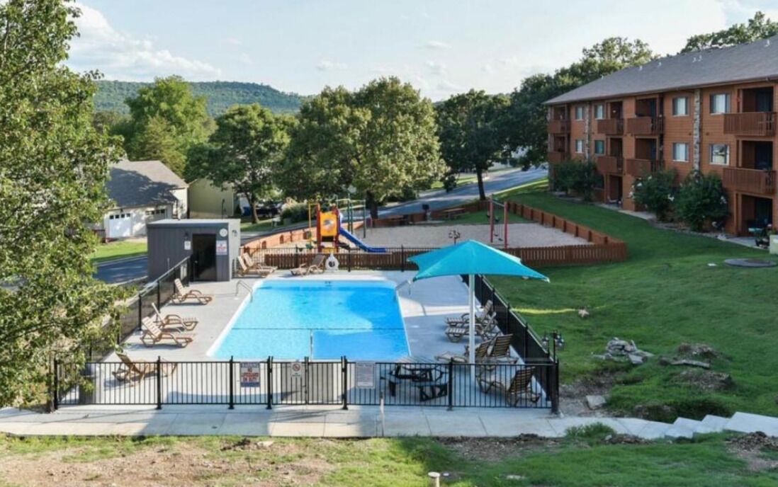 Ein Swimmingpool mit Rutsche, umgeben von Liegestühlen und einer überdachten Sitzgruppe.