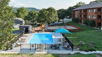 Ein Swimmingpool mit Rutsche, umgeben von Liegestühlen und einer überdachten Sitzgruppe.