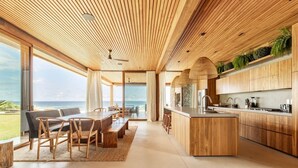 A modern kitchen with wooden cabinetry, a central island, and a view of the ocean.