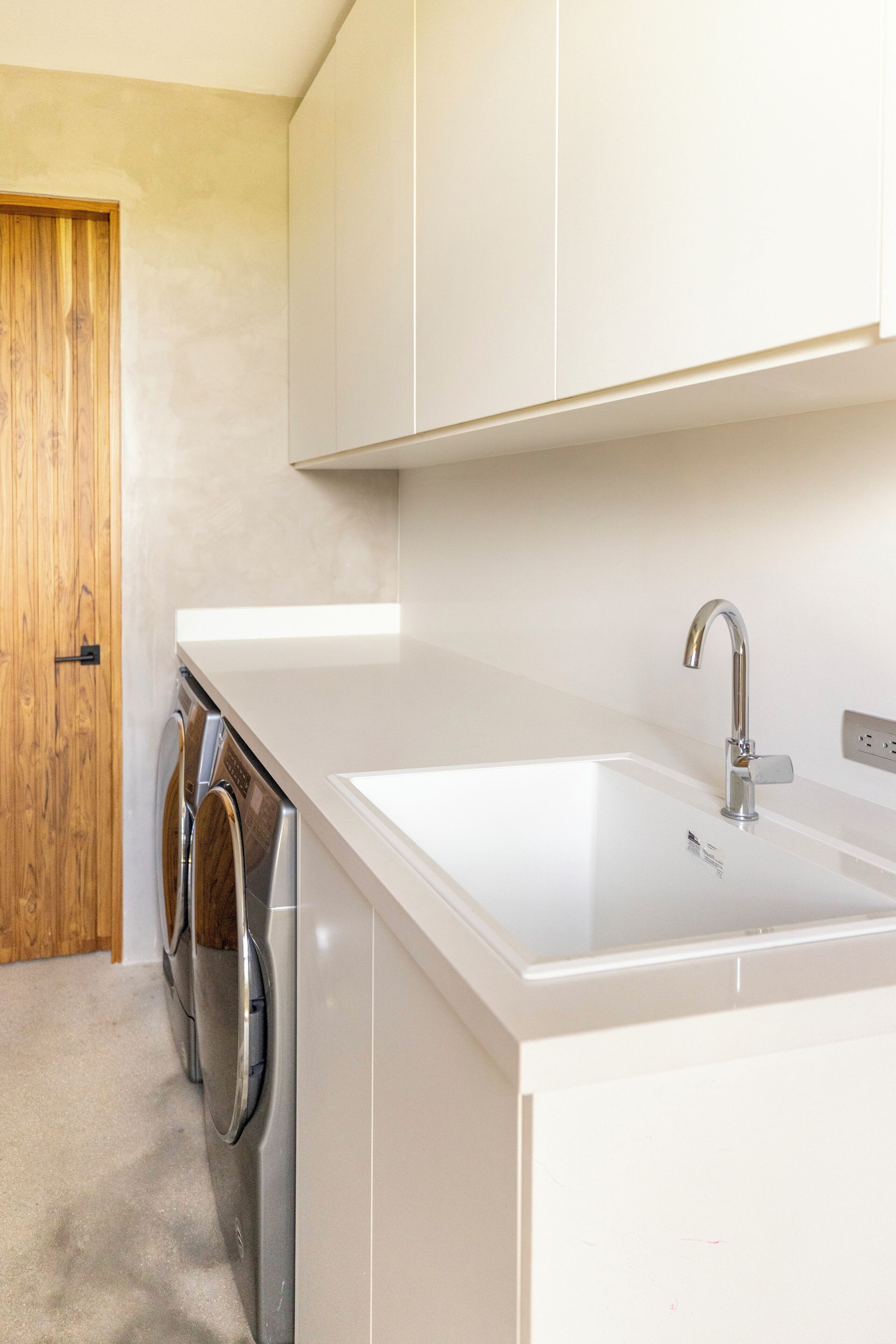 A modern kitchen with a white countertop, stainless steel appliances, and a wooden door.