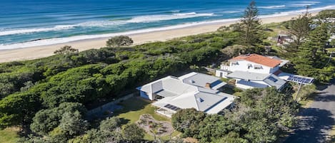 A coastal property with a large house, solar panels, and a view of the ocean.