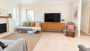 Una sala de estar con sofá, televisión, aparador de madera, sillón y chimenea.