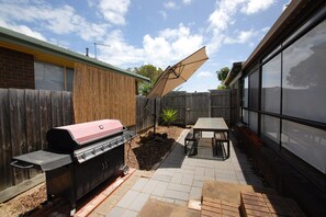 A backyard with a barbecue grill, a table, and a covered area. - airconditioner,coonara,sunroom,bbq,cosy,pets,boats,jetski (Melbourne)