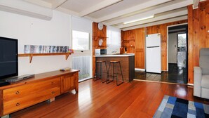 Une cuisine moderne avec des meubles en bois, un réfrigérateur, un four à micro-ondes et un évier. On y trouve également un coin bar avec des tabourets et un téléviseur posé sur un meuble en bois.