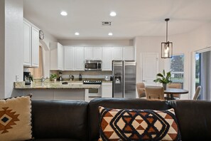 A modern kitchen with white cabinets, stainless steel appliances, and a dining area with a table and chairs.