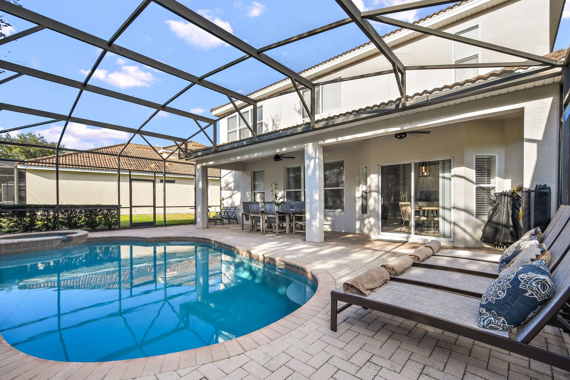 A covered outdoor swimming pool with lounge chairs and a patio area.
