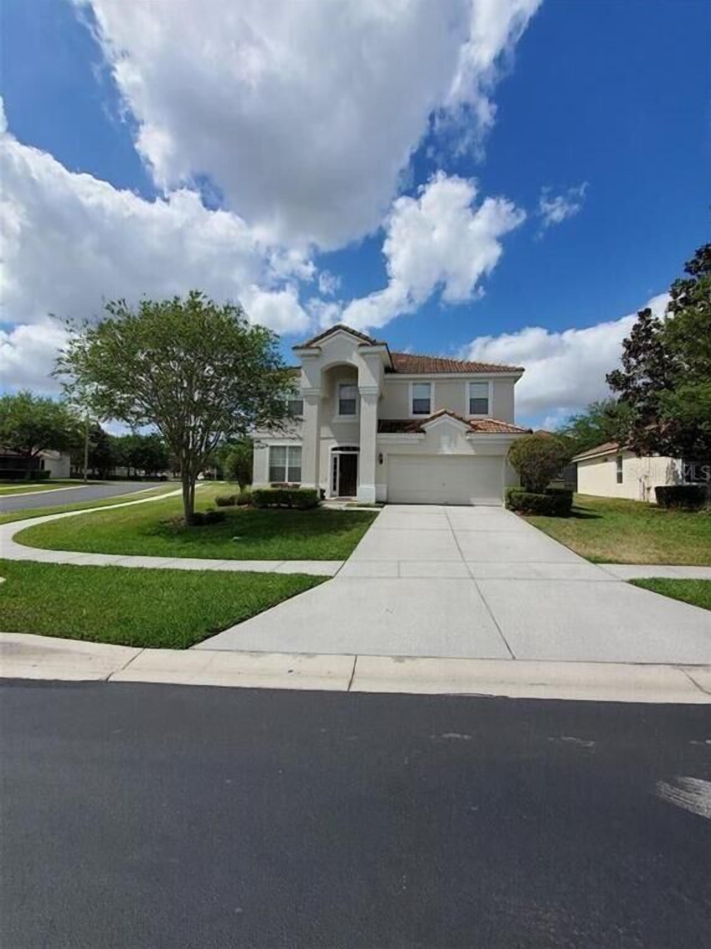 A two-story house with a front driveway and a well-maintained lawn.