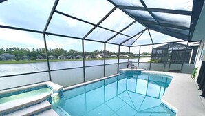 An indoor swimming pool with clear glass walls, a covered area, and steps leading into the pool. - Lake House | Disney | Huge Pool&Spa | Gated (Kissimmee)