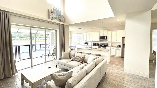 A spacious living area with a large sofa, a coffee table, and a view of the outdoor pool. - Lake House | Disney | Huge Pool&Spa | Gated (Kissimmee)