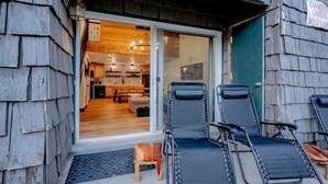 L’extérieur est en bois et une porte-fenêtre coulissante donne accès à la cuisine et à l’espace de vie. On trouve trois fauteuils confortables à l’extérieur.