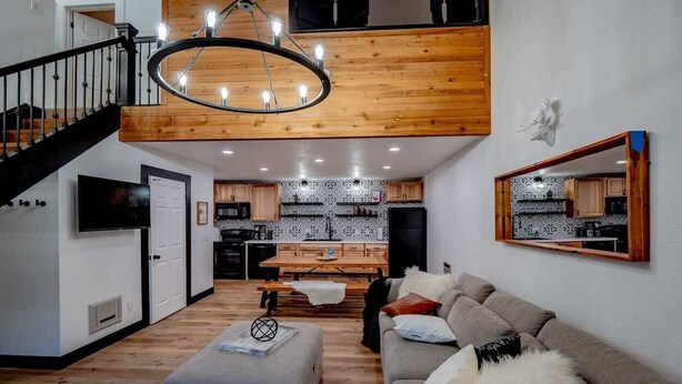 Un salon moderne avec un escalier, un plafond en bois et une cuisine en arrière-plan.