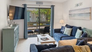 A living room with a sofa, a coffee table, and a television. - Renovated Beach Villa 14F: Gated Community near Golf and Bike Trails (Hilton Head Island)
