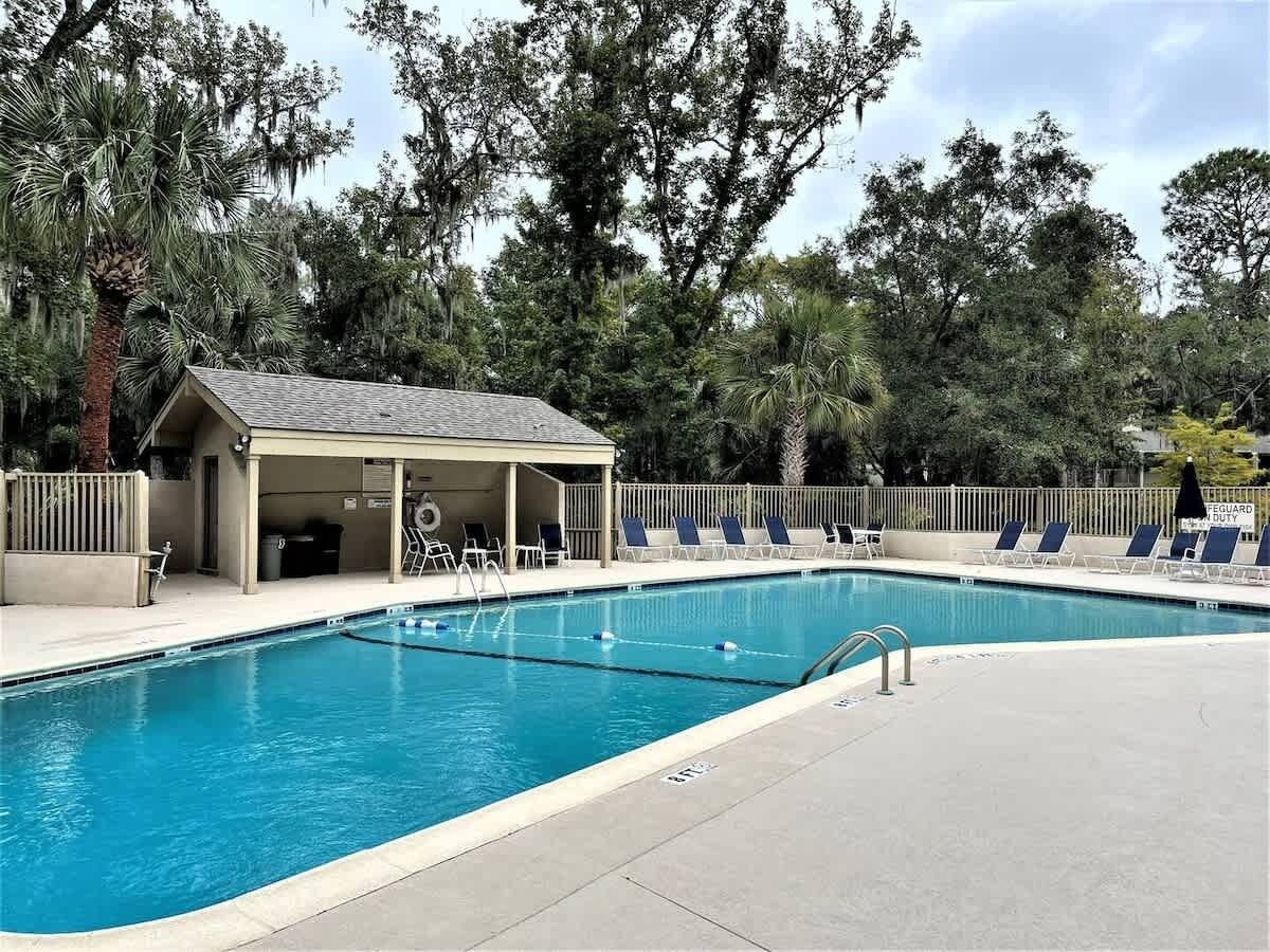 Une piscine avec des chaises longues et un espace salon abrité.