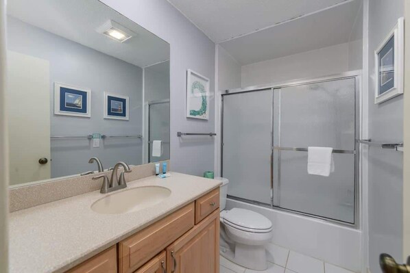 Un baño con lavabo, espejo, inodoro y ducha.