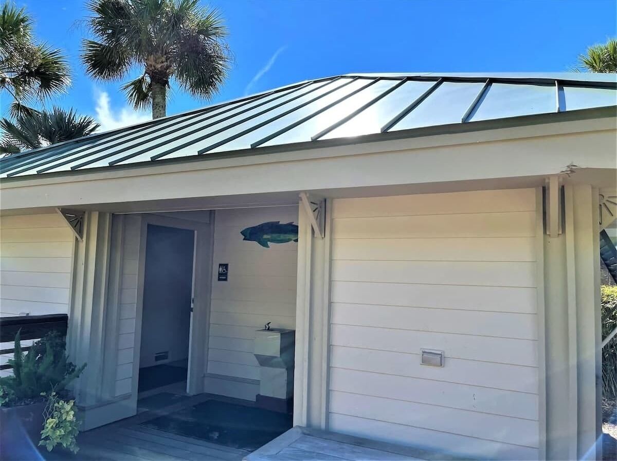 A single-story building with a garage door, a small porch, and a door leading to a bathroom.