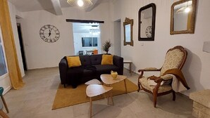 Een woonkamer met een bank, fauteuil, salontafel en open haard.