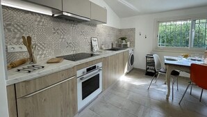 Een moderne keuken met een ingebouwde oven, een wasmachine en een eethoek met uitzicht.