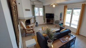 Een ruime woonkamer met een open haard, een bank, een salontafel en een televisie.