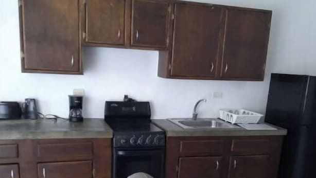Una cucina con mobili in legno, un fornello, un lavello e un frigorifero.