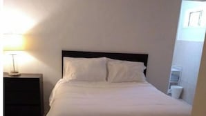 A neatly made bed in a room with a tiled floor and a nightstand with a lamp. - The beach is our back yard apt #5B (Bahamas)