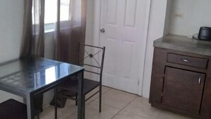 Une petite cuisine comprenant une table et des chaises, une porte et un plan de travail avec des appareils de cuisine.