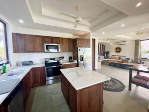 A modern kitchen with wooden cabinets, stainless steel appliances, and a marble countertop.