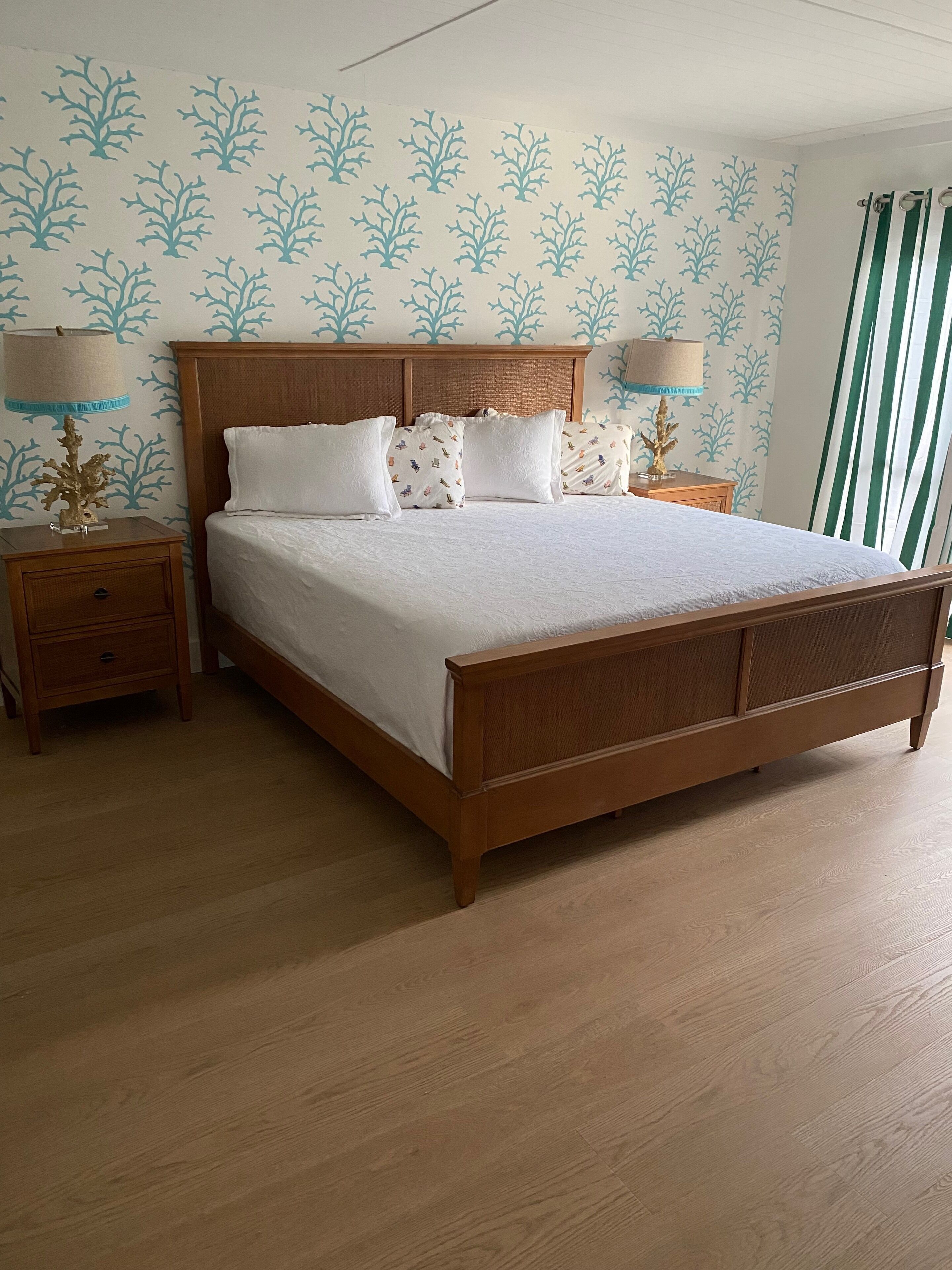 A bedroom with a wooden bed, white bedding, and a nightstand with a lamp.