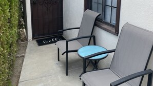 A patio with two chairs and a small table, a brown gate, and a window with blinds. - Villa M - 1bedroom villa with kitchen, steps from downtown Palm Springs! 🍒 (Palm Springs)