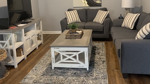 A living room with a grey sofa, a white coffee table, a TV on a white cabinet, a ceiling fan, and a large abstract painting. - Center of Madison , Near bridge street , Dublin Park (Madison)