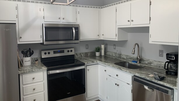 A modern kitchen with white cabinets, a stainless steel microwave, an oven, a dishwasher, and a granite countertop. - Center of Madison , Near bridge street , Dublin Park (Madison)