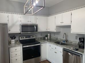 A modern kitchen with white cabinets, a stainless steel microwave, an oven, a dishwasher, and a granite countertop. - Center of Madison , Near bridge street , Dublin Park (Madison)