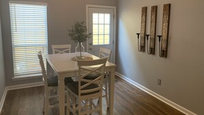A dining area with a white table and chairs, a vase with a plant, and wall-mounted decorative items. - Center of Madison , Near bridge street , Dublin Park (Madison)