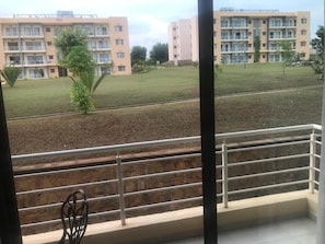 Enjoy the view of the surrounding residential area from this balcony with a seating area and metal railing.