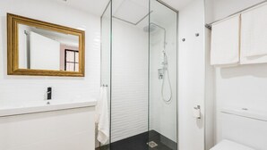 A modern bathroom with a glass-enclosed shower, a white sink, and a gold-framed mirror. - SPECTACULAR GRAN VIA CHUECA EXTERIOR (Madrid)