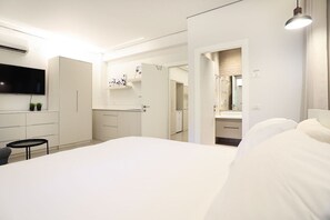 Un dormitorio moderno con una cama grande, un televisor de pantalla plana montado en la pared y un vestidor.
