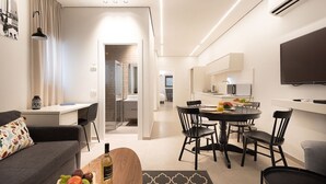 Un salon moderne comprenant un canapé, une table à manger avec des chaises, un téléviseur et un appareil de climatisation.