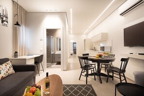 A modern living room with a sofa, a dining table with chairs, a TV, and an air conditioning unit.