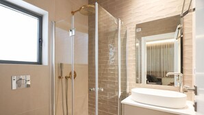 Une salle de bain moderne avec une douche à parois de verre, un lavabo blanc et un grand miroir.