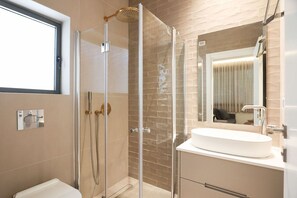 A modern bathroom with a glass-enclosed shower, a white sink, and a large mirror.
