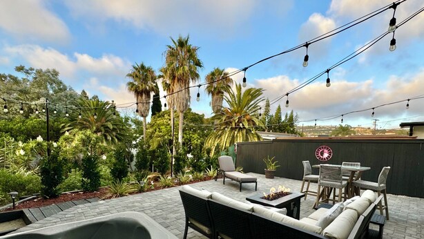Eine Terrasse im Freien mit Whirlpool, Sitzgelegenheit und Lichterkette.