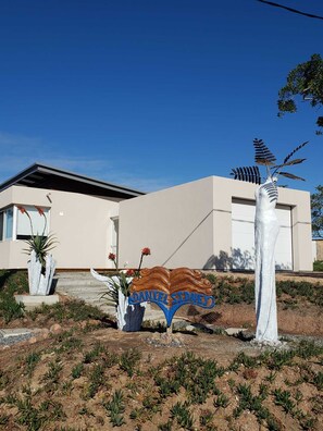 A modern house with a minimalist design, a driveway, and a decorative metal sign.