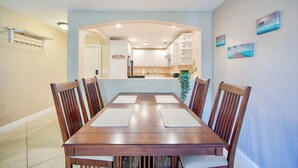 A dining area with a wooden table and chairs, a kitchen in the background, and a view of the sea through a window. - Lake view spacious 2bdr CONDO 7 min by the BEACH (Sarasota)