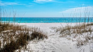 Une plage de sable fin, avec une eau d’un bleu limpide et un ciel dégagé.