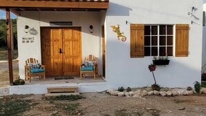 A white building with a wooden door and two wooden chairs outside. - Private 2 bedroom Casitas with pool. Azteca villas (Treasure Beach)