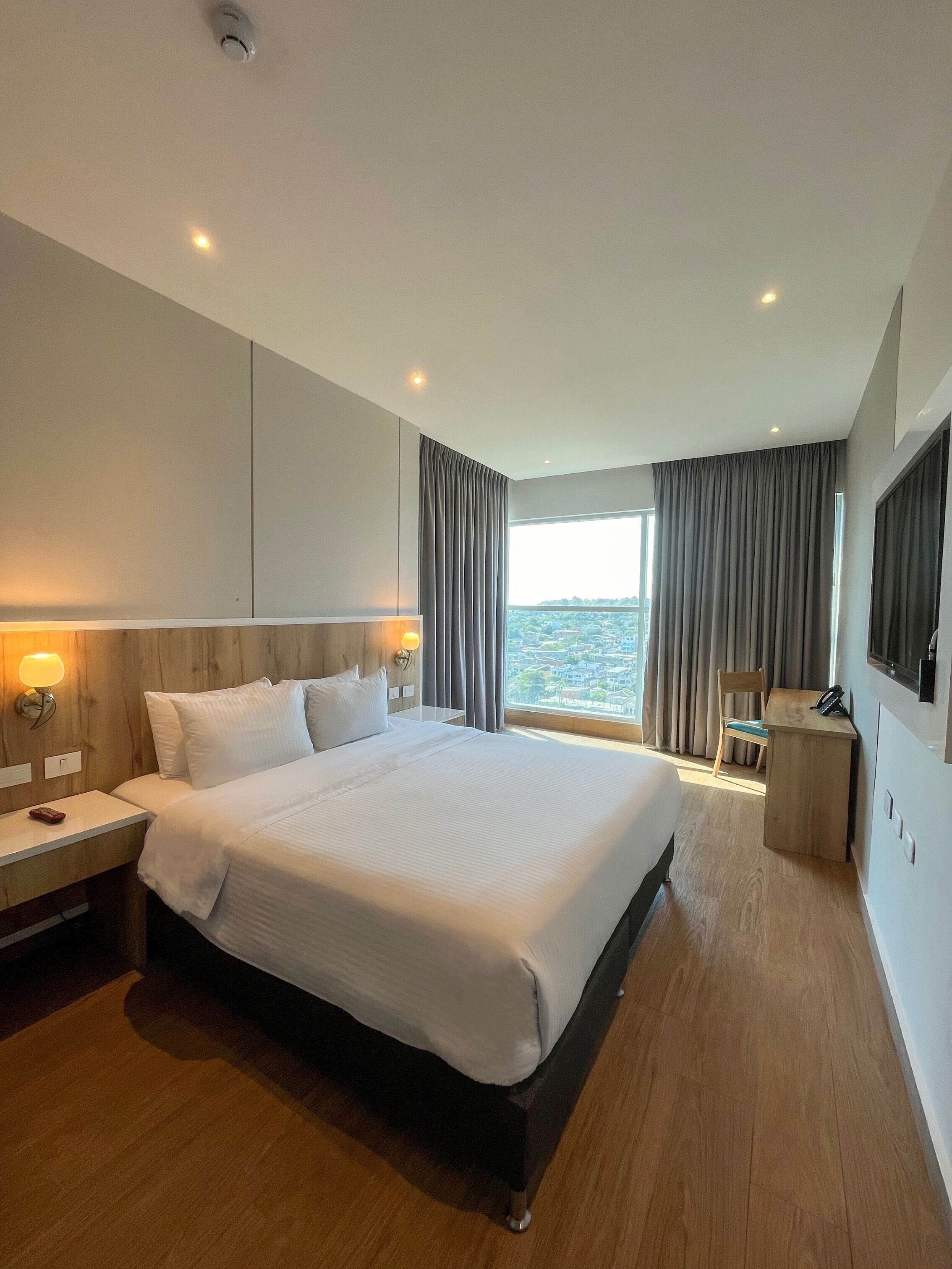 Et moderne hotelværelse med en stor seng, et skrivebord og havudsigt.