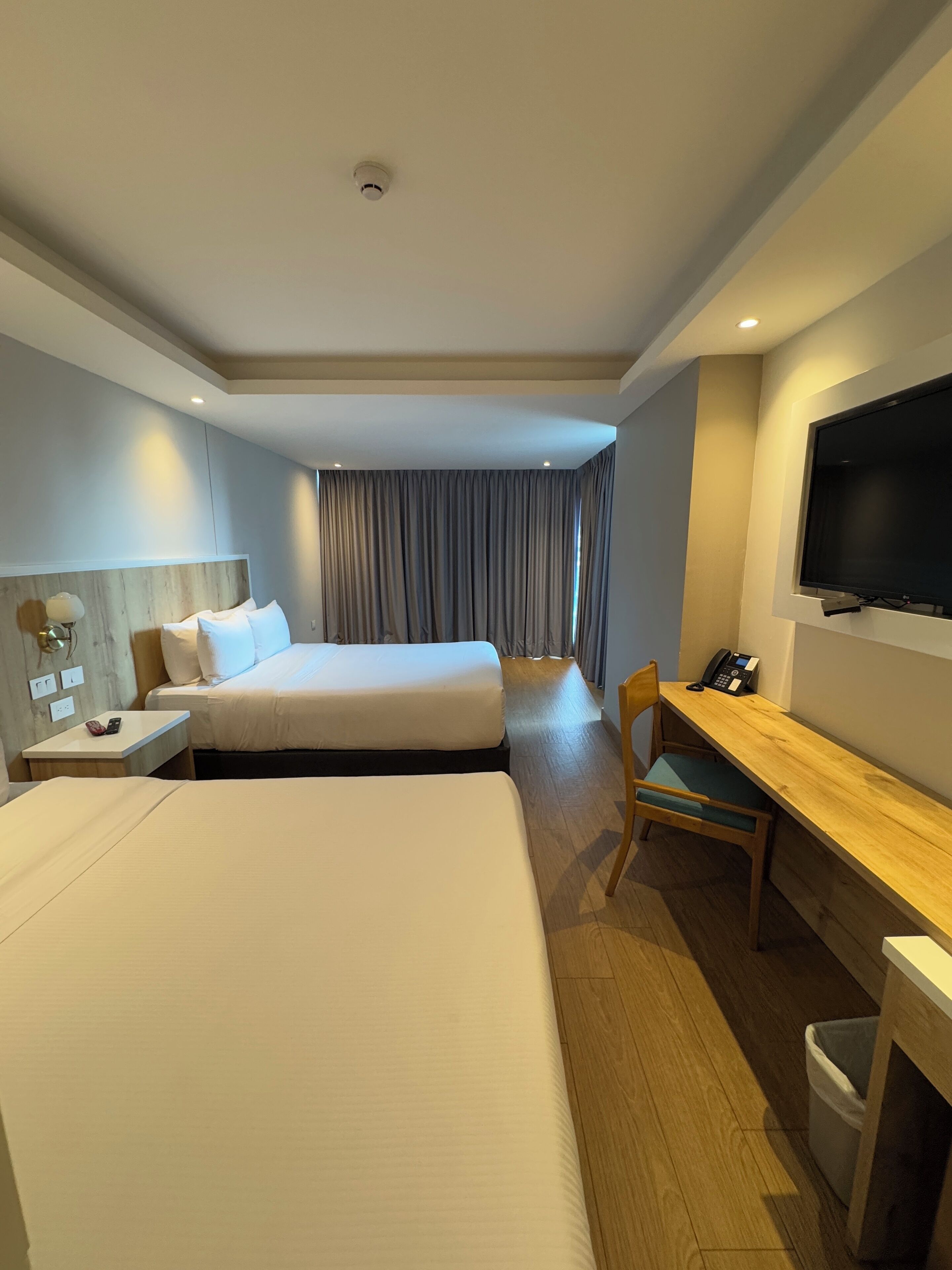 Habitación de hotel con dos camas, un escritorio, una silla, un televisor y un teléfono sobre el escritorio.