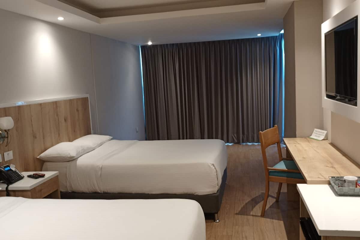 Hotelkamer met twee bedden, een bureau, een stoel, een televisie en een telefoon op het nachtkastje.